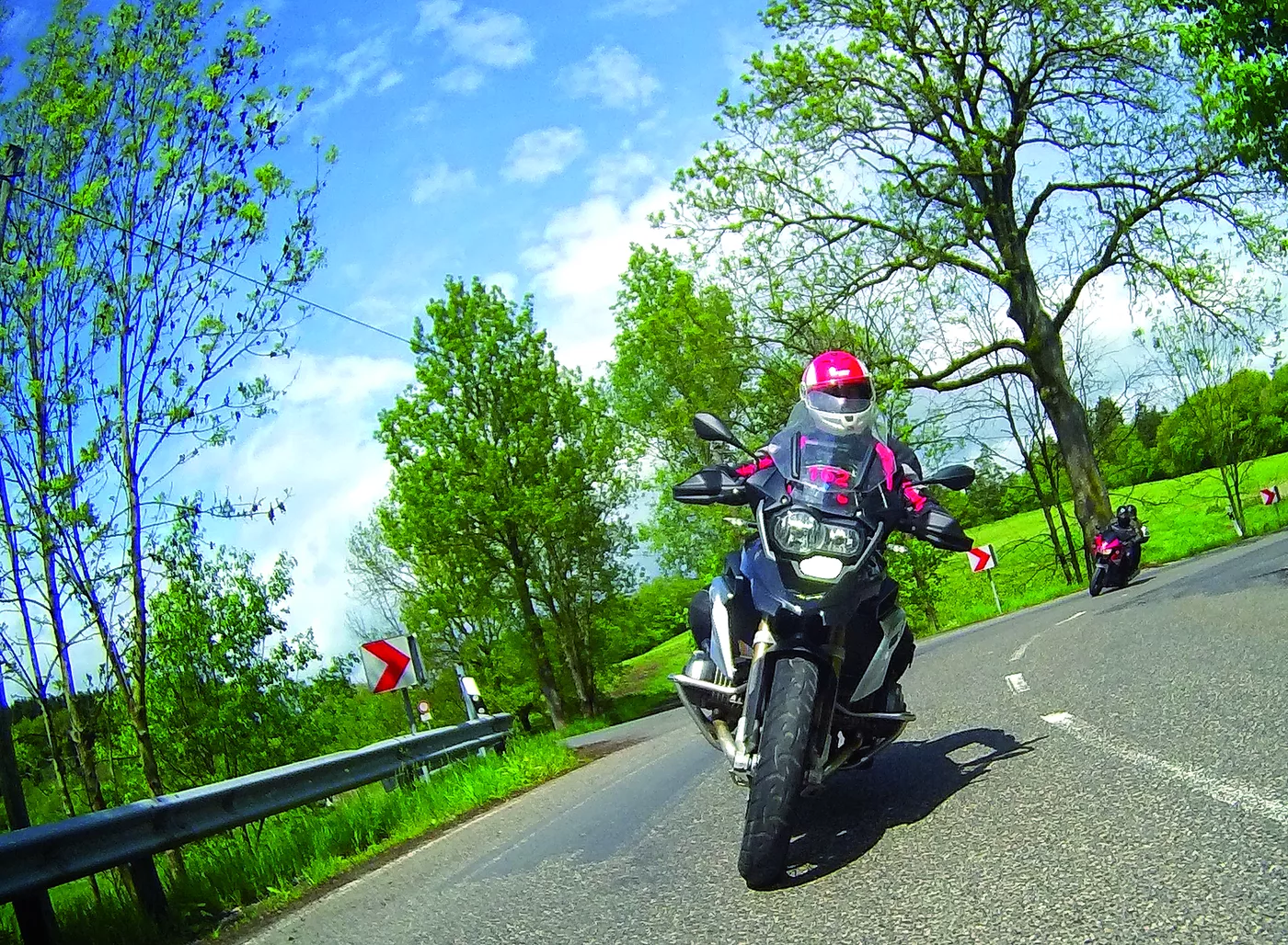 Motorrad in Schräglage auf einer von Bäumen gesäumten Straße
