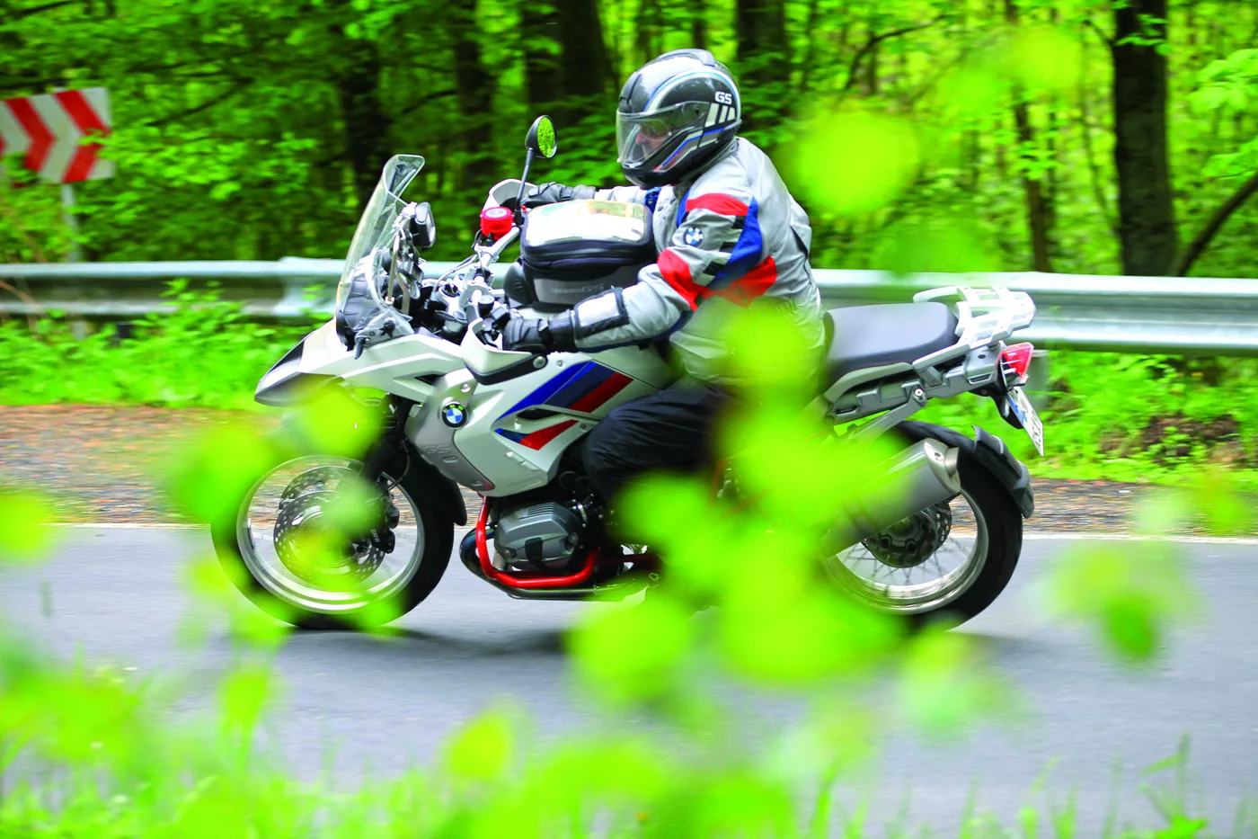 Motorrad in einer Kurve, im Vordergrund grüne Blätter Motorrad in einer Kurve, im Vordergrund grüne Blätter